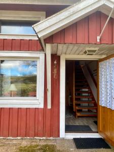 una casa roja con una puerta roja y escaleras en Lya med utsikt, en Henån