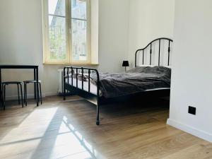 sypialnia z łóżkiem, oknem i drewnianą podłogą w obiekcie Apartamenty Maj Sokołowsko w mieście Sokołowsko