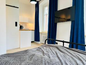 a bedroom with a bed with blue curtains and a tv at Apartamenty Maj Sokołowsko in Sokołowsko
