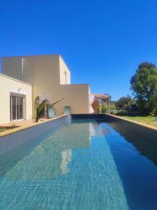 a swimming pool with blue water in front of a house at Aux amoureux de Provence in Fox-Amphoux