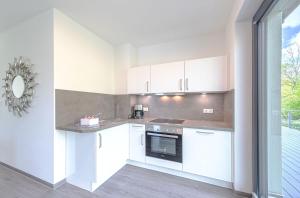 a kitchen with white cabinets and a stove top oven at Ferienwohnung Shanti-Suite - Sauna & Seegrundstück in Krakow am See