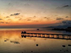 twee mensen zitten op een pier bij zonsondergang bij Casa vacanze VIA ROMA 57 in Marsala +6 foto's