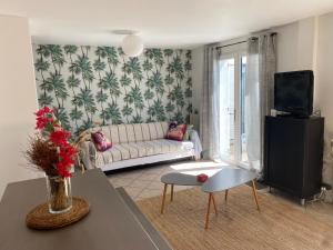 ein Wohnzimmer mit Sofa und Fernseher in der Unterkunft Gites d'Ici et d'Ailleurs 1 & 2 -famille ou groupe- Dépendances dans propriété proche Bordeaux et Bassin Arcachon in Saint-Morillon