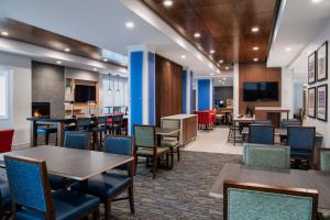 a dining room with tables and chairs and a television at Holiday Inn Express Hotel & Suites Saskatoon, an IHG Hotel in Saskatoon