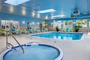 uma piscina num quarto de hotel com cadeiras e uma piscina em Holiday Inn Express Hotel & Suites Saskatoon, an IHG Hotel em Saskatoon