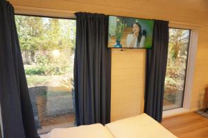 a tv on a wall in a room with a window at Casuta Cires - Therme & Aeroport Otopeni in Corbeanca +23 photos