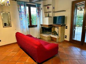 un sofá rojo en la sala de estar con chimenea en Villa Giovannino tra Firenze, Arezzo e Siena, en Terranuova Bracciolini