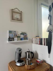 um balcão de cozinha com comodidades para preparar café numa mesa em La petite maison em Gasny