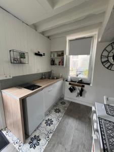 eine Küche mit einer Theke, einem Waschbecken und einem Fenster in der Unterkunft La petite maison in Gasny