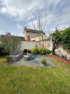 eine Terrasse mit einem Sofa und einem Tisch im Hof in der Unterkunft La petite maison in Gasny