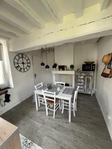 uma sala de jantar com mesa e cadeiras e um relógio em La petite maison em Gasny