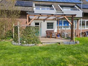 a wooden pergola with a table in a yard at Fewo Minsen in Wangerland