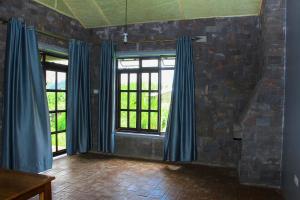 an empty room with blue curtains and windows at Lake Chahafi Resort in Kisoro