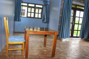 una mesa de madera y una silla en una habitación con ventanas en Lake Chahafi Resort, en Kisoro