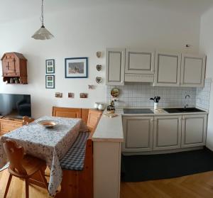 eine Küche mit weißen Schränken und einem Tisch darin in der Unterkunft La Stella Alpina in Gossensaß