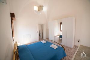a bedroom with a blue bed in a white room at Zaira House in Torre Suda +108 photos