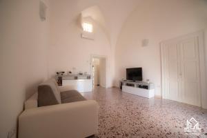 a white living room with a couch and a tv at Zaira House in Torre Suda