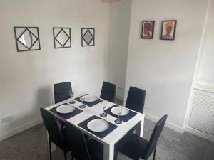 a dining room table with chairs and a white table with wine glasses at Home Away From Home Local To A Lot Of Amenities in Stoke on Trent