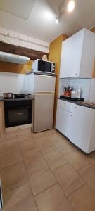 cocina con electrodomésticos blancos y suelo de baldosa. en Gîte La Grange 9 pers, en Saint-Georges-sur-Cher