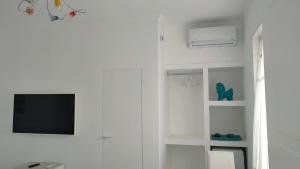 a living room with a tv and a white wall at B&B "Raggio di Sole" in Le Castella