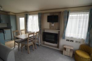 a living room with a table and chairs and a television at Stunning river view 2 bedroom caravan with decking in Hunstanton
