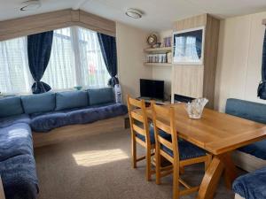 赫徹漢的住宿－Budget 3 Bedroom Caravan with Decking at Heacham，客厅配有桌子和蓝色沙发