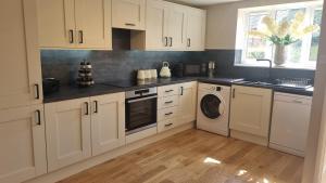 a kitchen with white cabinets and a washer and dryer at Wheelwright's Cottage in Yeaveley