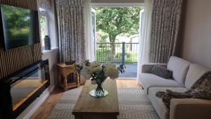 a living room with a vase of flowers on a coffee table at Wheelwright's Cottage in Yeaveley