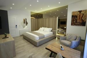 een slaapkamer met een bed, een stoel en een tafel bij Reign Hotel in Vorë