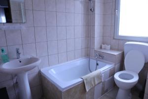 La salle de bains est pourvue d'un lavabo, d'une baignoire et de toilettes. dans l'établissement Taxi Hostel, à Otopeni