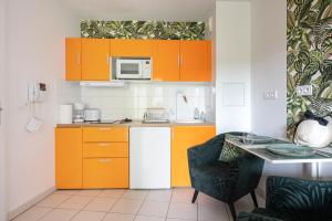 eine kleine Küche mit orangefarbenen Schränken und einem Tisch in der Unterkunft Joli appartement dans Eco quartier résidentiel in Saint-Ouen