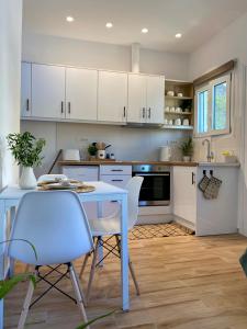 a kitchen with white cabinets and a table and chairs at Oliva - 1 bedroom apartment in Benitses
