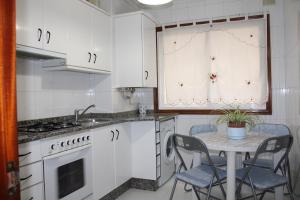 een keuken met witte kasten en een tafel met stoelen bij Apto Peteiro in Ponteareas