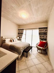 1 dormitorio con 1 cama y 1 silla en Skilpadtepel, en Henties Bay