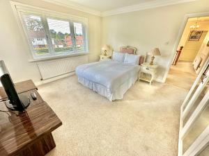 1 dormitorio con 1 cama y TV. en Golf Course View - Large Four Bed Home with Garden and Parking - New Forest and Beach Links en Ferndown