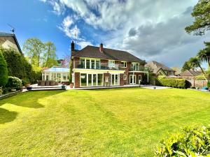 a house with a large lawn in front of it at Golf Course View - Large Four Bed Home with Garden and Parking - New Forest and Beach Links in Ferndown