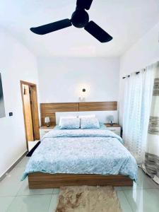 a bedroom with a bed with a ceiling fan at Timba-Pekinoracom in Cotonou
