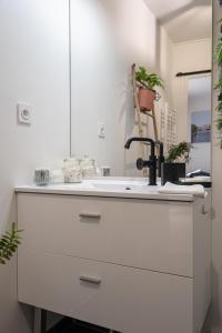 bagno bianco con lavandino e specchio di Joli appartement dans Eco quartier résidentiel a Saint-Ouen