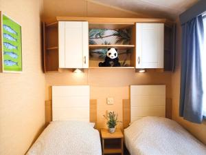 um quarto com duas camas e um urso panda numa prateleira em Chalet Melrose - Camping Parc Valrose em La Londe-les-Maures