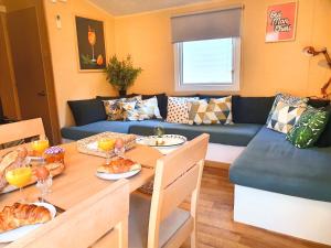 uma sala de estar com uma mesa e um sofá azul em Chalet Melrose - Camping Parc Valrose em La Londe-les-Maures