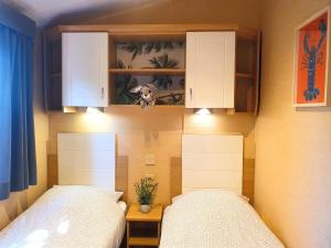 Duas camas num pequeno quarto com duas camas de solteiro. em Chalet Melrose - Camping Parc Valrose em La Londe-les-Maures