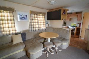 a living room with a couch and a table at pets go free family 3 Bed Caravan with Decking in Hunstanton
