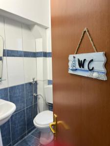 ein Bad mit WC und eine Tür mit Schild in der Unterkunft Glauk Apartment in Berat