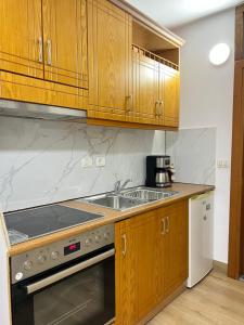 eine Küche mit Holzschränken und einem Waschbecken in der Unterkunft Glauk Apartment in Berat