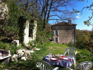 - une table et des chaises dans une cour avec une maison dans l'établissement Moulin de Bapaumes, à Nérac