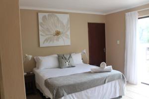 Kruger Bush Retreat في مارلوث بارك: غرفة نوم بسرير مع صورة زهرة على الحائط