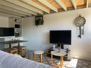 Gite d'ici et d'ailleurs 2 في Saint-Morillon: غرفة معيشة مع أريكة وساعة على الحائط