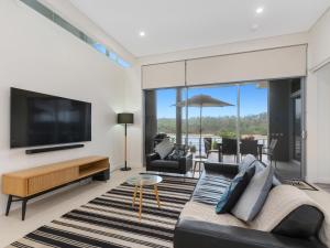 a living room with a couch and a tv at Bare Feet Retreat in Kingscliff