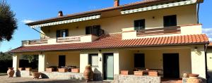 a large yellow building with a red roof at Appartamenti Pian d'Alma in Punta Ala
