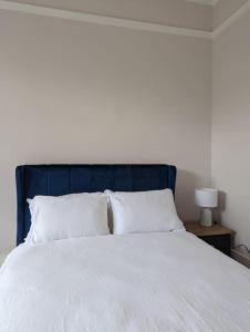 a white bed with a blue headboard and white pillows at Studio flat in York in York